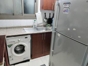 a kitchen with a refrigerator and a washing machine at Lovely 2Bhk Family Apartment in Ajman in Al Ḩamīdīyah