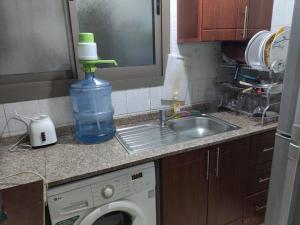 eine Küchentheke mit einer Waschmaschine und einer Flasche Wasser in der Unterkunft Lovely 2Bhk Family Apartment in Ajman in Al Ḩamīdīyah