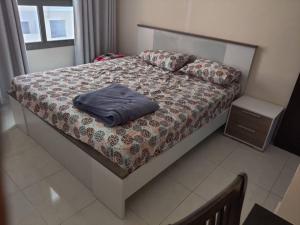 a bed with a blue pillow on it in a bedroom at Lovely 2Bhk Family Apartment in Ajman in Al Ḩamīdīyah