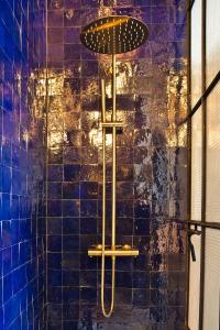 a shower with an umbrella on a blue tiled wall at 2 pièces à Bastille in Paris
