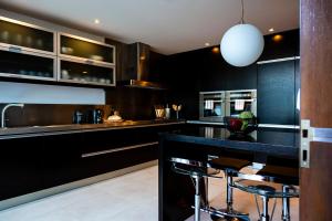 eine Küche mit schwarzen Schränken und eine Bar mit Hockern in der Unterkunft Casa da Barra in Vila Nova de Gaia