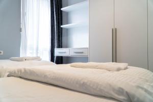 2 letti con lenzuola bianche in una stanza con finestra di Signature apartment 5 a Tirana