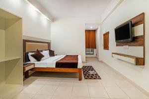 Hotel South Indian في نيودلهي: غرفة نوم بسرير وتلفزيون بشاشة مسطحة