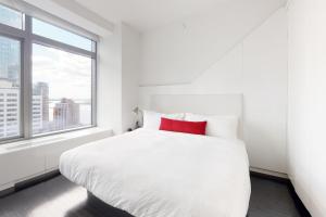 a white bed with a red pillow in a room with a window at Blueground Tribeca roof deck nr WTC NYC-1377 in New York