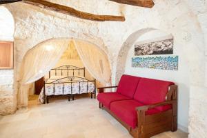 een woonkamer met een rode bank en een bed bij Trullo Ulivo in Martina Franca