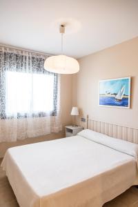 a bedroom with a white bed and a window at Llevant 3 in L'Ampolla