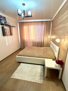 - une petite chambre avec un lit et une table dans l'établissement Элитные Апартаменты в центре города, à Kostanay