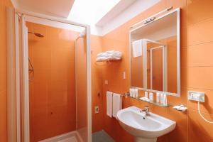 un bagno arancione con lavandino e specchio di Nicolaus Club Magna Grecia a Metaponto