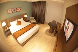 a hotel room with a bed and a flat screen tv at LIMERIDGE SIGNATURE HOTEL in Ikeja