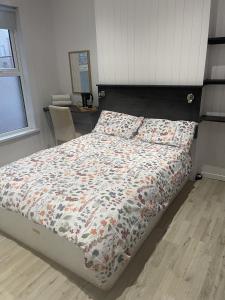a bedroom with a bed with a floral comforter at OYO Queens Quarter in Belfast