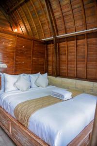 a large bed in a room with wooden walls at Abing Dalem - Villa Manggis in Tabanan