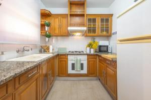 a kitchen with wooden cabinets and a sink and a stove at La Caseta de Sant Pol in Sant Feliu de Guixols