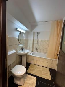Un baño con inodoro, lavabo y bañera. en Apartament de 3 camere zona Obcini, en Suceava