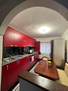 cocina con armarios rojos y mesa de madera en Apartament de 3 camere zona Obcini, en Suceava