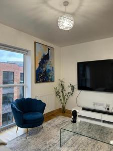 Il comprend un salon doté d'une chaise bleue et d'une télévision à écran plat. dans l'établissement Stunning 2-Bed Apartment in Dartford, à Dartford