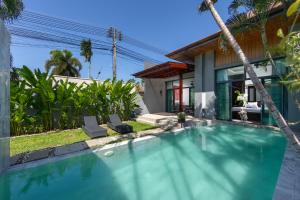 a swimming pool in front of a house at Onyx Villas by TropicLook in Nai Harn Beach
