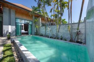 a swimming pool in front of a house with palm trees at Onyx Villas by TropicLook in Nai Harn Beach
