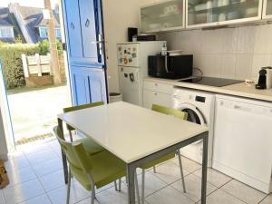 een keuken met een tafel en stoelen en een vaatwasser bij Jolie petite maison proche mer in Le Pouliguen
