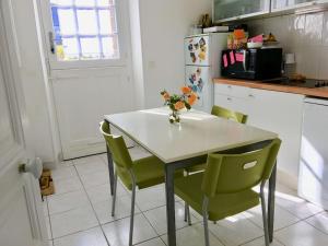 een keuken met een tafel met stoelen en een koelkast bij Jolie petite maison proche mer in Le Pouliguen