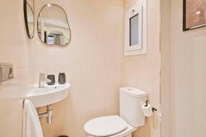 a white bathroom with a toilet and a sink at Citytrip Palau de la Música in Barcelona