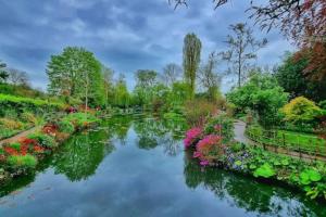 a view of a garden with flowers and a river at Insolite Escapade avec Spa privatif - Climatisé in Pacy-sur-Eure