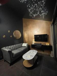 een woonkamer met een bank en een tv bij Insolite Escapade avec Spa privatif in Pacy-sur-Eure