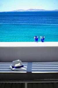 a hat and two glasses on a balcony with the ocean at Mykonos Riviera Hotel & Spa, a member of Small Luxury Hotels of the World in Tourlos