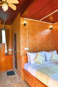 a bedroom with a bed with a brick wall at Abing Dalem - Villa Nangka in Tabanan