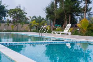 una piscina con sedia e panca accanto ad essa di Hotel Nilkantha a Mandarmoni