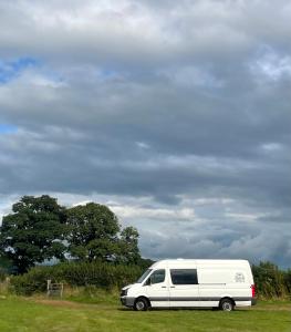 una furgoneta blanca estacionada en un campo bajo un cielo nublado en Viv The VW Campervan - Drive Away, en Neath