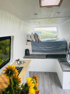 Habitación pequeña con cama y mesa. en Viv The VW Campervan - Drive Away, en Neath