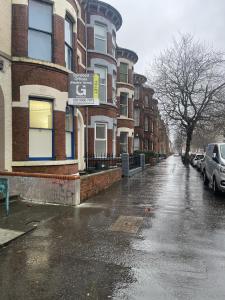 uma rua da cidade molhada com edifícios e carros em um dia chuvoso em OYO Queens Quarter em Belfast