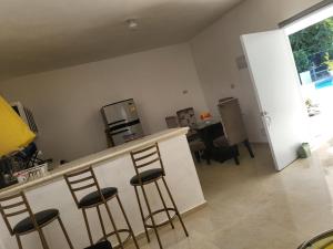 a kitchen with a bar with four stools at Villa sonia in Juan Barón