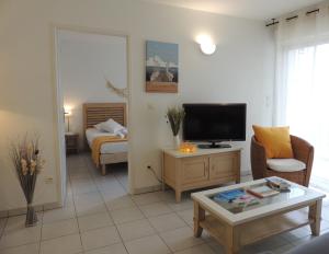 Lagrange Vacances - Villa d'Este في أركاشون: غرفة معيشة مع تلفزيون وأريكة وطاولة