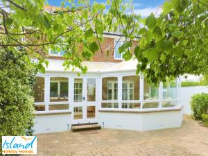 une maison blanche avec un banc devant elle dans l'établissement Gate House, à Bembridge