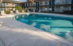 a swimming pool with chairs and a building at Motel 6-Ft. Pierce, FL in Fort Pierce