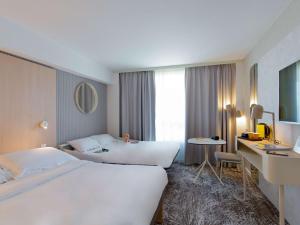 a hotel room with two beds and a desk at Novotel Aix-en-Provence Pont de L'Arc in Aix-en-Provence