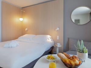 a hotel room with a bed and a bowl of food on a table at Novotel Aix-en-Provence Pont de L'Arc in Aix-en-Provence