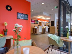 a restaurant with orange walls and tables and chairs at ibis Heilbronn City in Heilbronn