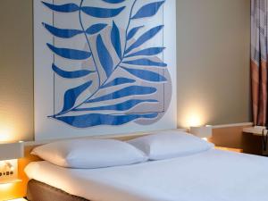 海爾布隆的住宿－海爾布隆宜必思酒店，一张带两个枕头的床和墙上的绘画