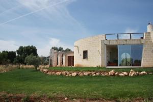 een stenen huis met een raam op een groen gazon bij trullo contemporaneo in Serranova