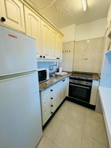 a kitchen with white cabinets and a white refrigerator at Cosy Apartment in the heart of Las Americas in Arona