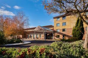 a building with a tree and flowers in front of it at DoubleTree by Hilton Swindon Hotel in Swindon