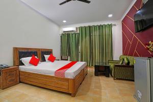 巴雷利的住宿－OYO Hotel Bonzer，一间卧室配有一张带红色枕头的床和电视。