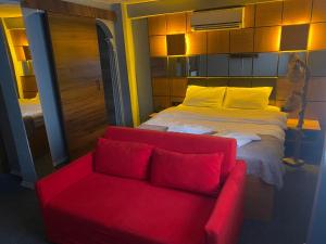 a red couch and a bed in a room at Kadıköy Linda Hotel in Istanbul
