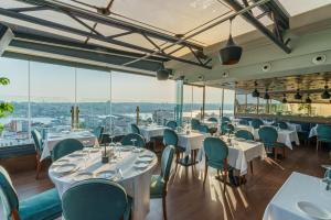ein Restaurant mit Tischen und Stühlen und großen Fenstern in der Unterkunft Anemon Koleksiyon Galata Otel in Istanbul