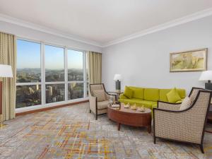 a living room with a couch and chairs and windows at Swissotel Al Maqam Makkah in Mecca