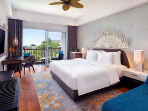 um quarto com uma grande cama branca e uma varanda em Grand Mercure Bali Seminyak em Seminyak