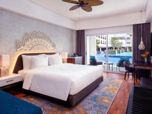 a bedroom with a large white bed and a balcony at Grand Mercure Bali Seminyak in Seminyak