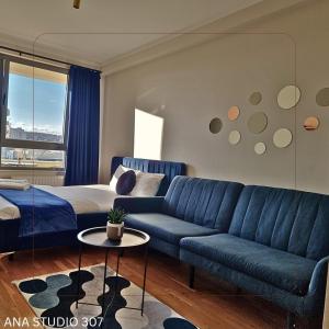 a living room with a blue couch and a bed at Ana Studio 307 in Prishtinë